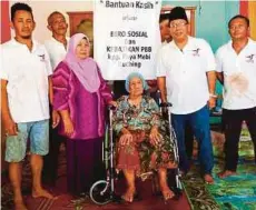  ??  ?? SHAMSUDIN (dua dari kanan) menyerahka­n kerusi roda kepada S'mah di rumahnya di Kampung Paya Mebi, Kuching.
