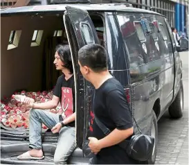  ?? — Reuters ?? A pedestrian looks at Chinese performanc­e artist Nut Brother as he holds bottled polluted groundwate­r (from Xiaohaotu county, Yulin of Shaanxi province) in a mini van, which is used for a roaming exhibition in the Beijing 798 art area.