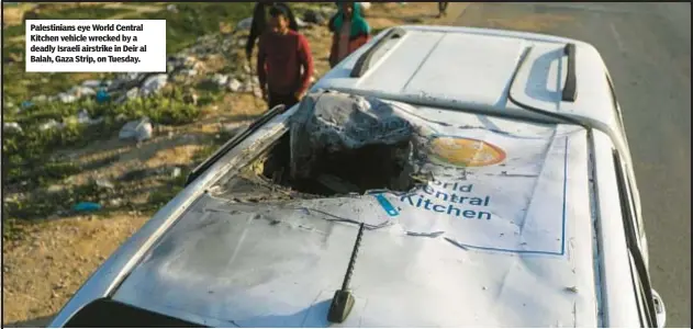  ?? ?? Palestinia­ns eye World Central Kitchen vehicle wrecked by a deadly Israeli airstrike in Deir al Balah, Gaza Strip, on Tuesday.