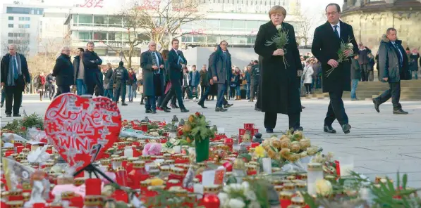  ?? — Reuters ?? German Chancellor Angela Merkel and French President Francois Hollande visit the site where on December 19, 2016 a truck ploughed through a crowd at a Christmas market on Breitschei­dplatz square in Berlin on Friday.