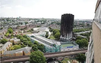  ??  ?? LONDON: Railway tracks run in front of the charred remains of the Grenfell Tower block in Kensington, west London yesterday, following the June 14 fire at the residentia­l building. Angry London residents heckled Prime Minister Theresa May and stormed...