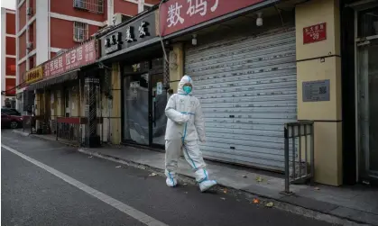  ?? ?? An epidemic control worker walks past closed shops in Beijing on Sunday. Photograph: Kevin Frayer/Getty Images