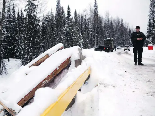  ?? ?? An RCMP officer looks on remnants of the Gidimt’en checkpoint near the Unist’ot’en Camp in Houston, B.C., late last week. Activists are vowing to step up protests targeting the $40-billion LNG Canada megaprojec­t.