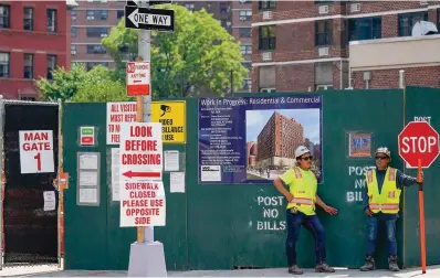  ?? The Associated Press ?? ■ Constructi­on workers help direct traffic Thursday outside a residentia­l and commercial building under constructi­on at the Essex Crossing developmen­t on the Lower East Side of Manhattan. America’s hiring boom continued last month as employers added a surprising 528,000 jobs despite raging inflation and rising anxiety about a recession.