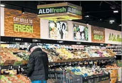  ??  ?? Shoppers choose produce at Aldi on Nov. 14 in Downers Grove.