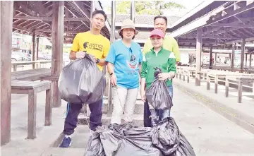  ??  ?? (From left) Addy, Jenifer, Doris and Ronald (at the back) with the bags of trash they collected at the tamu ground.