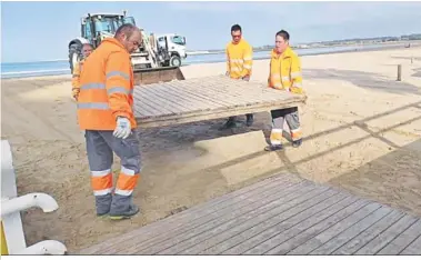  ?? . ?? Personal municipal, instalando las pasarelas de madera en una playa de El Puerto.