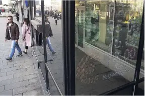  ?? AP ?? People walk past an exchange office screen showing the currency exchange rates, in Moscow, Russia, on Tuesday, April 10. The rouble has plunged for the second day in a row following fresh US sanctions against Russia.