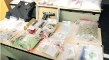  ?? JIM WELLS ?? Police display a variety of drugs, cash and weapons seized during a recent operation in Calgary.
