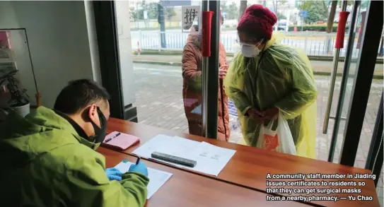  ??  ?? A community staff member in Jiading issues certificat­es to residents so that they can get surgical masks from a nearby pharmacy. — Yu Chao