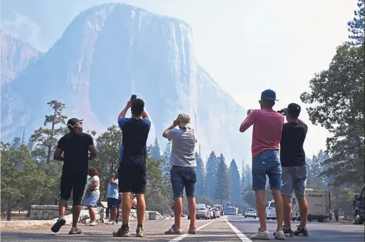  ?? — AP ?? Hail to the chief: Visitors taking pictures of El Capitan through a thin veil of smoke after Yosemite Valley re-opens in Yosemite National Park, California.