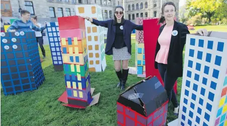  ??  ?? Kwantlen Polytechni­c University students Natasha Lopes, left, and Caitlin McCutchen join other post-secondary students setting up cardboard apartment buildings at the legislatur­e as part of a student housing protest.