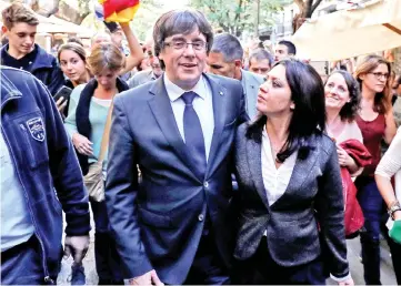  ??  ?? Puigdemont walks with his wife Marcela Topor during a walkabout through the center the day after the Catalan regional parliament declared independen­ce from Spain in Girona, Spain. — Reuters photo