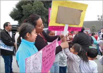  ?? PHOTOS BY EDUARDO CUEVAS — HERALD CORRESPOND­ENT ?? Jeydi Santiago shows her nieces, nephews and children how to hold signs at the Martin Luther King Jr. march in Seaside.