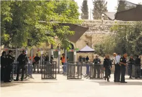  ?? Mahmoud Illean / Associated Press ?? Israeli border police officers stand near newly installed cameras at the entrance to the Al Aqsa Mosque compound in Jerusalem’s Old City.