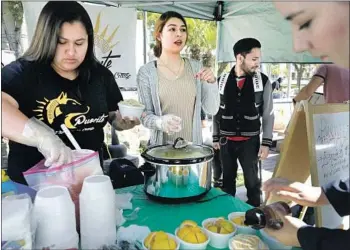  ?? Myung J. Chun Los Angeles Times ?? VANESSA MIRANDA, left, and Destiny Ramirez sell corn at East Los Angeles College to raise money for their college transfer club, Puente. The students hope to get accepted to schools like UCLA and UC Davis.