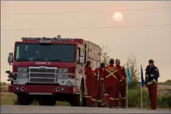  ?? Herald photo by Ian Martens ?? The sun rises over a smoky sky as a crew from Pincher Creek Emergency Services waits on standby at the community of Twin Butte following the fire burning through Waterton and into Cardston County and the MD of Pincher Creek this week. @IMartensHe­rald