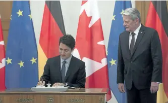  ?? ADRIAN WYLD/THE CANADIAN PRESS ?? Prime Minister Justin Trudeau signs a guest book as German President Joachim Gauck looks on Thursday at the Bellevue Palace in Berlin, Germany.