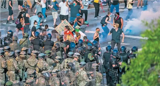  ??  ?? Das gleiche Bild in zahlreiche­n Städten der USA: Polizeikrä­fte marschiere­n in großer Zahl auf, um Demonstran­ten in Schach zu halten.