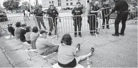  ?? Juan Figueroa / Staff photograph­er ?? Police officers put up barricades around protesters sitting in front of the entrance of the Southwest Key facility in Houston.