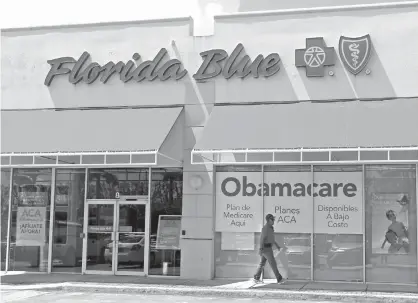  ?? Associated Press file photo ?? ABOVE: A person walks by a health care insurance office on July 27 in Hialeah, Fla. Health insurance shoppers faced a new deadline, rising prices and fewer options for help in many markets when the Affordable Care Act’s main enrollment window for 2018...