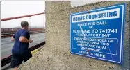  ??  ?? A man jogs past a sign about crisis counseling on the Golden Gate Bridge.
(AP/Eric Risberg)