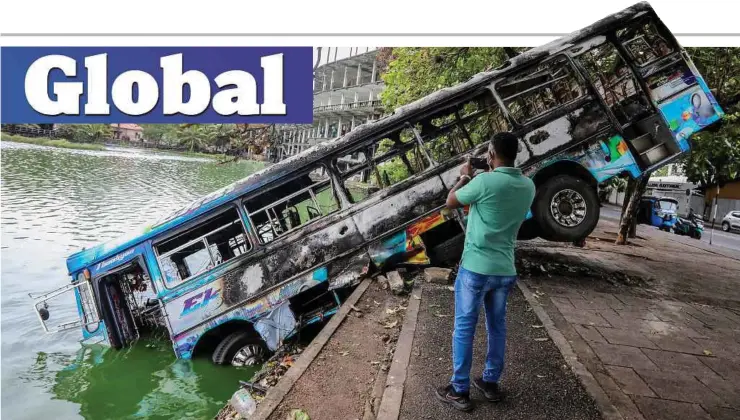  ?? ?? SEORANG lelaki mengambil gambar bas yang dibakar dan dibiarkan di laluan awam dalam pertempura­n di antara penyokong kerajaan dan penunjuk perasaan di Colombo, Sri Lanka.