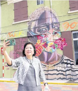  ?? ?? Mari Pangestu takes a selfie in front of a mural in downtown Kingston.