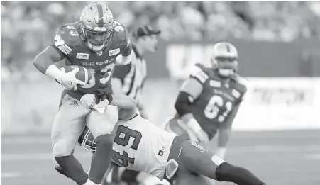  ??  ?? Blue Bombers running back Andrew Harris, a standout in his junior football career with the Vancouver Island Raiders, breaks a tackle by Calgary’s Alex Singleton Friday night in Winnipeg.