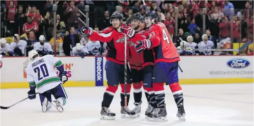  ?? ROB CARR/ GETTY IMAGES ?? Mike Green of the Washington Capitals celebrates his game- winning goal in the third period on Friday with teammates Nicklas Backstrom, left, Jack Hillen, second from right, and Tom Wilson, right, while Canucks forward Chris Higgins drops to his knees...