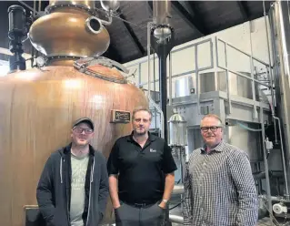  ??  ?? Le distillate­ur Matt Strickland et les actionnair­es Jean Dubé et Denis Guindon, devant l’alambic qui sert à distiller l’alcool produit à partir de l’orge de la ferme de Mirabel.