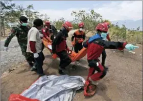  ?? DITA ALANGKARA — THE ASSOCIATED PRESS ?? Rescue workers carry a body to be buried at a mass grave for earthquake and tsunami victims in Palu, Central Sulawesi, Indonesia, Friday.