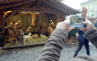  ??  ?? Violato Un turista fotografa il presepe del mercatino di Natale di Bolzano, uno dei simboli del periodo dell’Avvento nel capoluogo