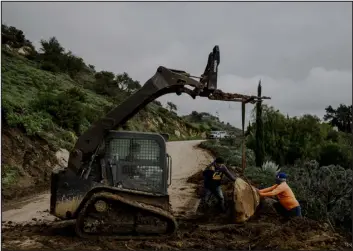  ?? PHOTOS BY MARK ABRAMSON — THE NEW YORK TIMES ?? Workers clear a trail of mud and debris from Bella Vista Drive in Montecito, Calif., which overlooks the ocean in Santa Barbara County on Jan. 11. Life in California often requires navigating the edge of disaster and natural beauty.