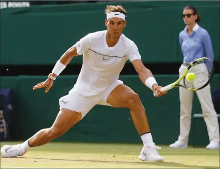  ?? Alastair Grant ?? The Associated Press No. 4 seed Rafael Nadal of Spain returns a shot to Russia’s Karen Khachanov during their Wimbledon singles match Friday in London. Nadal won to advance to the round of 16, where he is joined by the other members of the Big Four of...