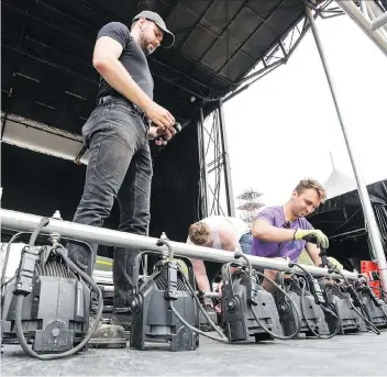  ?? BRANDON HARDER ?? Volunteers Ryan Allen, left, Frank Nordstrom, centre and Justin Palmier work on a bank of lights as they helped to dismantle the stage used for Regina Folk Fest in Victoria Park on Monday.