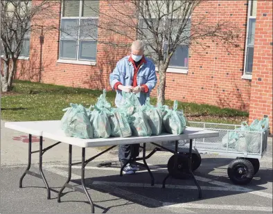  ?? H John Voorhees III / Hearst Connecticu­t Media ?? .
Volunteer Emie Riley helps distribute lunch and breakfast bags at Berry School on April 1 in Bethel.