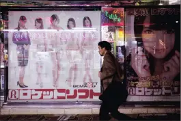  ??  ?? A man walks by ads in the Akihabara area of Tokyo.