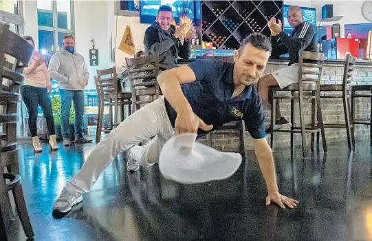  ?? JENNIFER LETT/SUN SENTINEL PHOTOS ?? Pizza chef Massimilia­no Stamerra dances, jumps and does freestyle pizza-throwing to lively music Jan. 9 as customers watch from their dining tables at GioiaEat in downtown Hollywood.