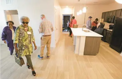  ?? JOE BURBANK/ORLANDO SENTINEL PHOTOS ?? Sanford Housing Authority Commission­er Victoria Murphy Nathan, second from left, and others tour one of the new units during the grand opening of SHA’s Somerset Landings Phase 2 in Sanford on Thursday.