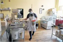  ?? Photos by Hyoung Chang, The Denver Post ?? Jason Burgett, co-owner of The Wooden Spoon, prepares to make madeleines at the cafe in Denver on Thursday. The cafe has made its operation entirely takeout, with a window at the front door for walk-ups and a pickup window around back for online orders.