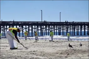  ?? JEFF GRITCHEN/THE ORANGE COUNTY REGISTER VIA AP ?? Workers clean oil from the sand, south of the pier, in Newport Beach, Calif., Tuesday, Oct. 5, 2021. A leak in an oil pipeline caused a spill off the coast of Southern California, sending about 126,000 gallons of oil into the ocean, some ending up on beaches in Orange County.