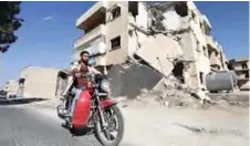  ??  ?? Syrian rapper Amir al-Muarri rides his motorcycle through a war-damaged street in the northweste­rn city of Maaret al-Numan in the Idlib province. — AFP photos