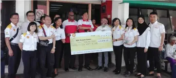  ??  ?? Shairan (fifth from right) presents the mock cheque to Tan as Ann Tan (fourth right) and others look on.