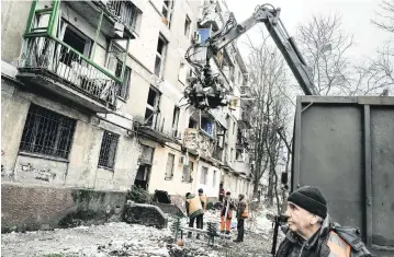  ?? WOJCIECH GRZEDZINSK­I For The Washington Post ?? A cleanup crew assesses the aftermath of a Russian rocket attack in Dnipro, Ukraine, on Friday. Ukraine officials say at least 39 civilians were killed by the Russian missile attacks on Friday.