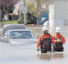  ?? JUSTIN TANG, CP ?? Workers pass a submerged car Wednesday in Gatineau, Que.