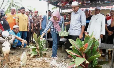  ??  ?? Painful goodbye: Nurul paying her last respects to Muhammad Adib at his grave while his father Mohd Kassim (second from right) and others look on at Kampung Tebengau in Kuala Kedah.