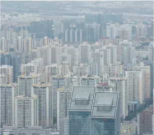  ?? (Reuters) ?? Residentia­l buildings are seen from a skyscraper during the afternoon haze in Beijing over the summer.