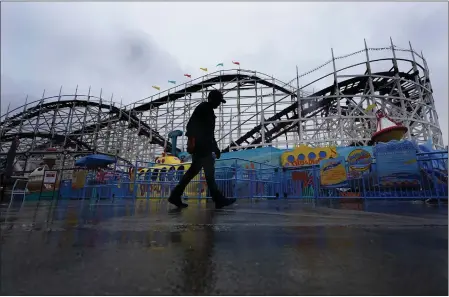  ?? GREGORY BULL — THE ASSOCIATED PRESS ?? A worker passes the roller coaster at Belmont Park as rain engulfs the area Tuesday in San Diego. California­ns are tired. Tired of the rain, tired of the snow, tired of stormy weather and the cold, relentless­ly gray skies that have clouded the Golden State nearly nonstop since late December.