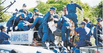  ??  ?? People protesting against restarting the constructi­on of helipads for US forces clash with riot police in Higashi-son, Okinawa. — AFP photo